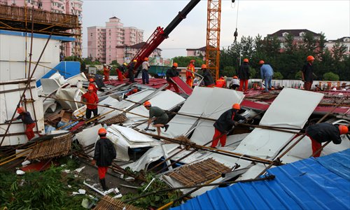 Workers search for missing  colleagues buried in a collapsed makeshift house at a construction site in Changning district Wednesday afternoon. The accident killed one and injured four others. Witnesses said strong winds caused the collapse. Photo: Cai Xianmin/GT