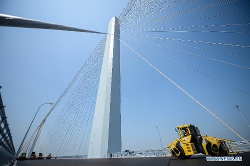 Workers pave asphalt on the surface of the Jiaxing-Shaoxing Sea-crossing Bridge in Shaoxing, east China's Zhejiang Province, May 24, 2013. The bridge is expected to be open to traffic by the end of June this year. It will halve the driving time from Shaoxing to Shanghai in east China after it is finished. (Xinhua/Xu Yu) 