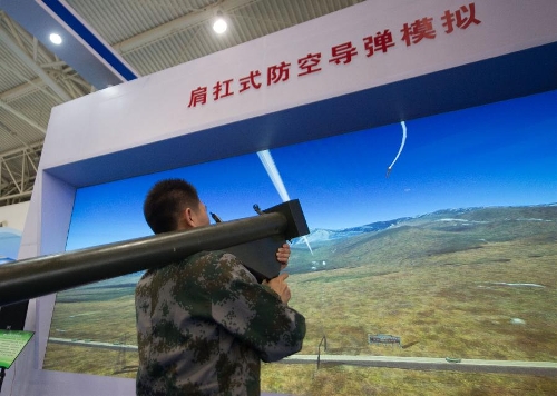 An assistant demonstrates a simulated shoulder-fired anti-aircraft missile during a science exhibition in Beijing, capital of China, May 19, 2013. The exhibition is a part of the National Science and Technology Week and will last till May 25. (Xinhua/Luo Xiaoguang)  