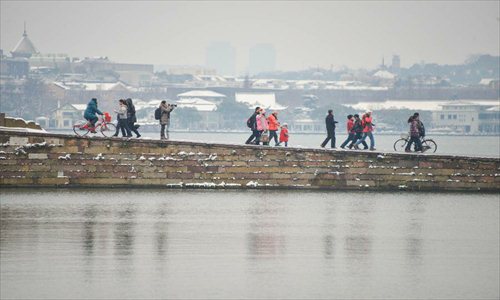 Tourists visit the West Lake after a snowfall in Hangzhou, capital of east China's Zhejiang Province, Feb. 8, 2013. A big range of snowfall enveloped Zhejiang Province on Friday. Photo: Xinhua