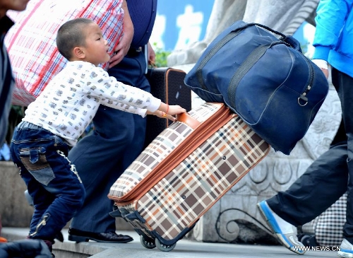 A little boy helps his family push the luggage case at Nanning train station in Nanning, capital of south China's Guangxi Zhuang Autonomous Region, Feb. 3, 2013. Many children travel with their families during the 40-day Spring Festival travel rush which started on Jan. 26. The Spring Festival, which falls on Feb. 10 this year, is traditionally the most important holiday of the Chinese people.Public transportation is expected to accommodate about 3.41 billion travelers nationwide during the holiday, including 225 million railway passengers. (Xinhua/Zhou Hua)