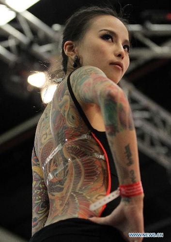 A woman from Asia shows her tattoo during the 21st International Tattoo Convention in Frankfurt, Germany, March 22, 2013. The Tattoo Convention kicked off on Friday and will last for three days. (Xinhua/Luo Huanhuan)