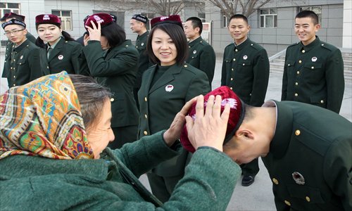 A local resident in Hami, Xinjiang Uyghur Autonomous Region, presents a traditional hat to  a soldier who is about to be demobilized from the military on Monday. Soldiers usually finish their tours of duty in China's military forces in late November. Photo: IC