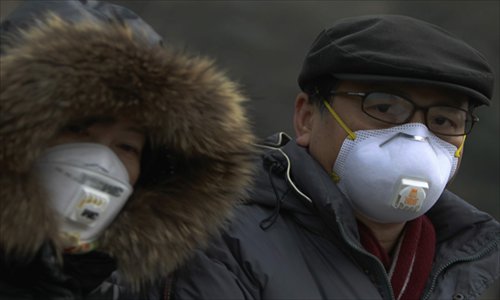 Two residents walk with masks as heavy smog engulfs the city of Beijing on Friday. Thick smog enveloped the Chinese capital where air quality was rated as 