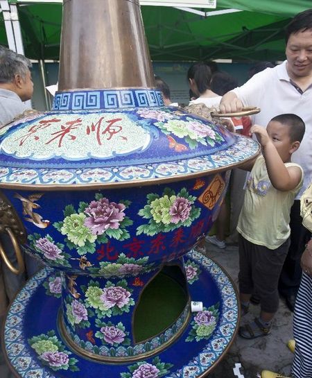 Visitors look at the model of a traditional Chinese hot pot during the 5th Muslim Diet Festival in Beijing, capital of China, August 19, 2012. About 30 local restaurants displayed dishes and cooking methods in the festival. Photo: Xinhua
