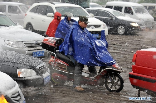 Citizens brave snow to ride on a snowy road in Taiyuan, capital of north China's Shanxi Province, April 19, 2013. A cold front brought snowfall to the city on April 19 morning. (Xinhua/Zhan Yan)