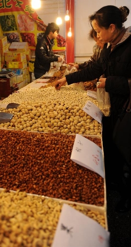 People buy nuts during the second Guiyang spring festival shopping fair in Guiyang, capital of southwest China's Guizhou Province, Jan. 19, 2013. The fair which would last from Jan. 19 to Feb. 6 attracts the participation of more than 400 enterprises, providing special goods for the Spring Festival use. (Xinhua/Tao Liang)  