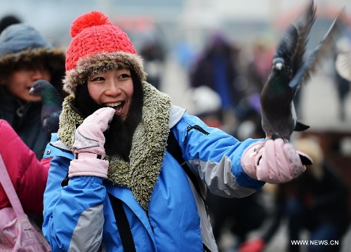 People play with pigeons in Harbin, capital of northeast China's Heilongjiang Province, Jan. 20, 2013. The temperature rise in Harbin enabled citizens to play with snow and ice in the outdoors. (Xinhua/Wang Kai)  