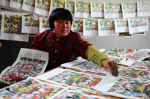 Craftsman Zhai Ruichen's wife Liu Shufang sorts New Year pictures they paints in Liaocheng, east China's Shandong Province, Jan. 9, 2013. The couple were busy painting New Year pictures recently to meet the demand in local market for the Spring Festival in February. (Xinhua/Zhang Zhenxiang) 