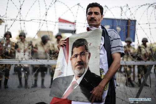 A supporter of Egyptian ousted president Mohamed Morsi holds up a portrait of Morsi as he attends a protest outside the Republican Guards headquarters in Nasr city, Cairo, Egypt, July 6, 2013. (Xinhua/Qin Haishi) 