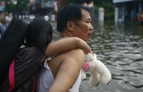 A citizen carrying his daughter walks on a flooded road in Ningbo, East China's Zhejiang Province, August 9, 2012. As typhoon Haikui landed in Hepu Town of Zhejiang's Xiangshan County early Wednesday, many roads and residential areas were waterlogged after torrential rains in Ningbo. Photo: Xinhua