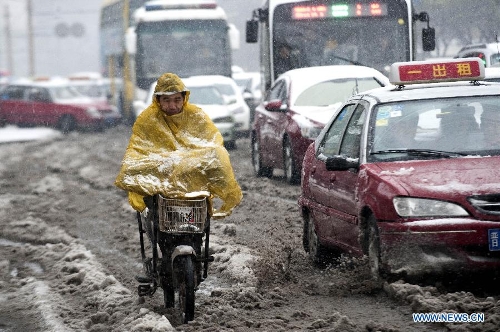 A citizen braves snow to ride on a snowy road in Taiyuan, capital of north China's Shanxi Province, April 19, 2013. The city witnessed a snowfall on April 19 morning. (Xinhua/Fan Minda)