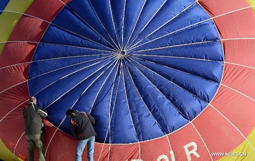 Balloonists inspect a balloon at the 35th International Ballon Festival in Chateau-d'Oex, Switzerland, Jan. 26, 2013. The 9-day ballon festival kicked off here on Saturday with the participation of over 80 balloons from 15 countries and regions. (Xinhua/Wang Siwei) 