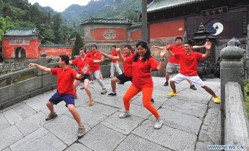 Visitors learn to play Taichi, a traditional Chinese shadow boxing, on the Wudang Mountain in central China's Hubei Province July 11, 2012. As the cradle of the Taoist culture, the Wudang Mountain was inscribed on the list of World Cultural Heritages in 1994. The scenery of the mountain attracts tens of thousands of visitors every year. Over 4 million tourists from at home and abroad are expected to visit the site this year. Photo: Xinhua