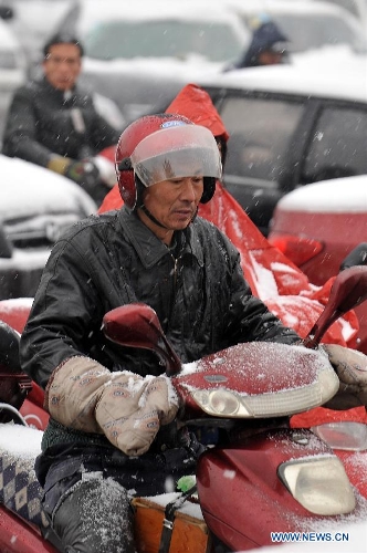 A citizen braves snow to ride on a snowy road in Taiyuan, capital of north China's Shanxi Province, April 19, 2013. A cold front brought snowfall to the city on April 19 morning. (Xinhua/Zhan Yan)