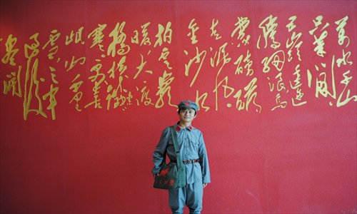 standing in front of a calligraphy-adorned wall in Liping, Guizhou Province