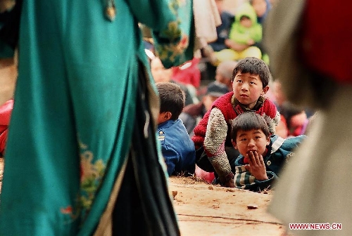  Children watch theatrical performance at an outdoor plaza in Weihui City, central China's Henan Province, Feb. 6, 2003. Village theatrical performances are usually given by local troupes during the Spring Festival or Chinese Lunar New Year in central China region. Chinese people who live in the central China region have formed various traditions to celebrate the Chinese Lunar New Year. (Xinhua/Wang Song)