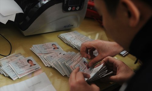 A police officer checks the ID cards of migrant workers left with a couple who helped them navigate the railway's online ticket purchasing website in Foshan, Guangdong Province. Photo: CFP