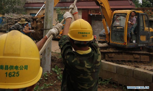 Staff members of power department repair power poles which were damaged by cyclone in Hongyuzhuang Village of Tongjing Township in Linyi City, east China's Shangdong Province, July 31, 2012. A cyclone swept the town on Tuesday night, breaking 22 telegraph poles and damaging houses and croplands. Photo: Xinhua