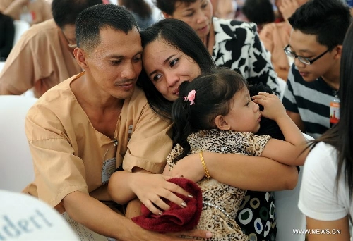 An unshackled prisoner embraces his wife and his daughter at Central Bangkwang Prison in Nonthaburi Province, Thailand, on May 15, 2013. More than 500 prisoners who committed serious crimes have had the handcuffs and foot shackles removed in Thailand. (Xinhua/Gao Jianjun) 