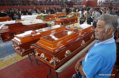 Relatives and friends stand beside the coffins of victims of a fireworks accident during a mass funeral at the village of Nativitas in Tlaxcala state, Mexico, on March 17, 2013. At least 13 people were killed and 154 others injured when a truck containing fireworks exploded during a Catholic procession in honor of a local patron saint. (Xinhua/Juan Mateo) 