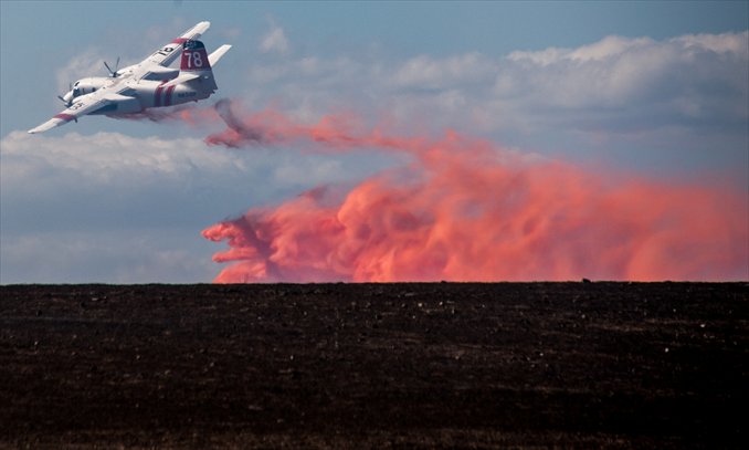 A plane drops water on a wildfire on Tuesday north of Santa Barbara near Santa Ynez, California. Forward progress had been stopped last night on a 170-acre grass fire in Santa Ynez, however, the blaze had not been contained as of press time, according to the Santa Barbara County Fire Department. Fire Captain David Sadecki said the Sheriff's Department had given an evacuation warning to 2,000 residents. Resources have been diverted from the Santa Barbara mountains to aid in containing the blaze. Photo: AFP