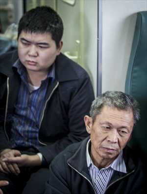 Wang and his son sit in the aisle of a train traveling back home on January 31.