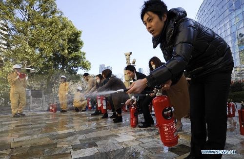 People attend a fire fighting drill in Tokyo, capital of Japan, on March 11, 2013. A drill to take precautions against natural calamities including medical emergency and fire fighting drills was held here to mark the two year anniversary of the March 11 earthquke and ensuing tsunami that left more than 19,000 people dead or missing and triggered a nuclear accident the world had never seen since 1986. (Xinhua/Kenichiro Seki) 