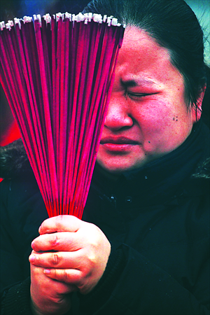 A woman holding a bundle of burning incense prays in Guiyuan Temple, Wuhan, Hubei Province.Photo: CFP