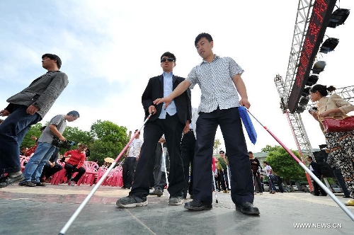 A worker helps a blind man to walk by using a crutch at the Yuhuangge Square in Yinchuan City, capital of northwest China's Ningxia Hui Autonomous Region, May 14, 2013. An activity aimed at helping the blind to walk was held here on Tuesday, in which more than 100 blind people were provided with crutches as they were helped to walk with them ahead of the 23rd national day for helping the disabled on May 19. (Xinhua/Peng Zhaozhi) 