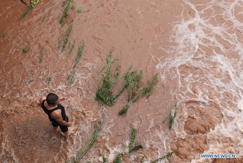 A man stands in flood water at GaoqiaoTown in Neijiang City, southwest China's Sichuan Province, July 1, 2013. Rainstorm-triggered natural disasters have hit nine provincial-level regions since June 29, leaving at least 39 dead and another 13 missing, China's Ministry of Civil Affairs (MCA) said Monday. The National Meteorological Center (NMC) issued a blue alert for rainstorms on Monday, forecasting heavy rain to continue in parts of north and southwest China over the next three days. The NMC also warned of downpours, thunderstorms and hail in south China's coastal Guangdong province and the island province of Hainan, which are bracing for approaching tropical storm Rumbia. (Xinhua/Lan Zitao)