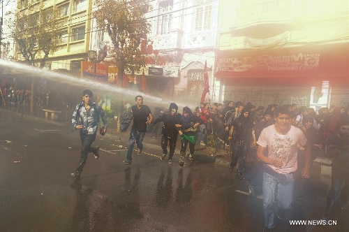 Protesters run to avoid water squirted by police during a protest called by the Worker's United Center (CUT, by its Spanish acronym), The School of Teachers, and social organizations, in Valparaiso, Chile, on May 21, 2013. The protest was performed simultaneously with the delivery of the last management report by president Sebastian Pinera before Chile's National Congress. (Xinhua/Jorge Villegas) 