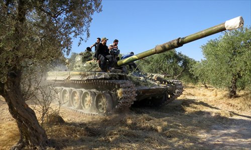 Rebel fighters sit on top of a tank that formerly belonged to the Syrian army during a battle with government forces in the rebel-held northwestern Syrian province of Idlib on Monday. Syrian President Bashar al-Assad warned Washington to brace for retaliation if US forces attack his war-torn country. Photo: AFP