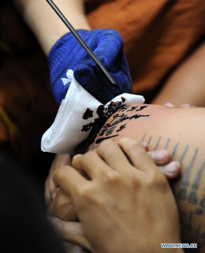 A Buddhist monk uses a needle to tattoo the arm of a man at Bang Phra temple in Nakhon Pathom province of Thailand, March 22, 2013. Thailand's traditional tattoo festival 