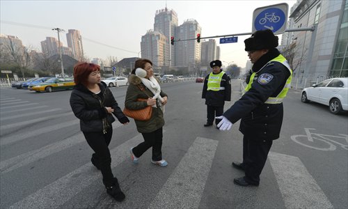 Two women are fined for jaywalking by police officers at Huizhong Lu, Chaoyang district Tuesday. Photo: CFP