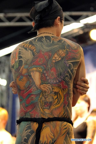 A man from Asia shows his tattoo during the 21st International Tattoo Convention in Frankfurt, Germany, March 22, 2013. The Tattoo Convention kicked off on Friday and will last for three days. (Xinhua/Luo Huanhuan)