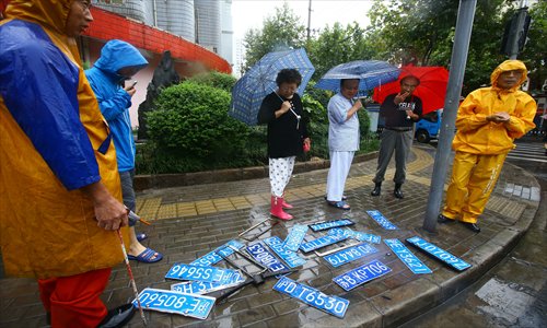 On Huayin Road, Putuo district, workers from the drainage department of the Shanghai Water Authority and bystanders look over lost car number plates washed up after the floods. Photo: Cai Xianmin/GT
