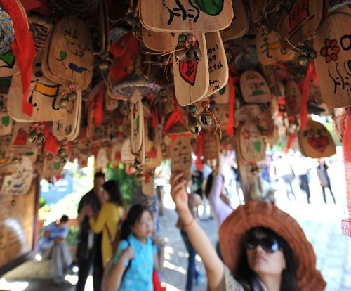 A woman looks at Dongba wind chimes of the Naxi ethnic group in the old town of Lijiang, southwest China's Yunnan Province, Aug. 8, 2012. The old town of Lijiang, a UNESCO World Heritage site with a history of more than 800 years, was formally licenced as the national 5A tourism attraction spot, the top one among China's tourism ranking system, on July 27, 2011. During the first six months of 2012, in total 8.0934 million people visited Lijiang, increasing by 55.93 percent year on year. The tourism industry's revenue of the same period reached 10.395 billion yuan ($1.634 billion), growing by 56.14 percent. Photo: Xinhua