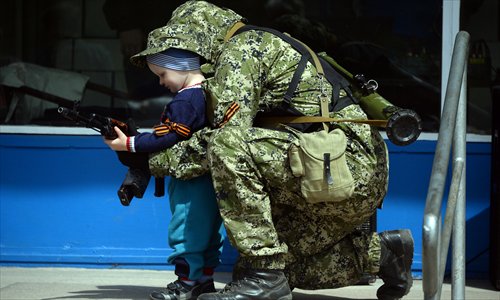 A pro-Russian man in military fatigues poses for a photo with a child on Monday as he stands guard outside a regional administration building seized in the night by separatists in Kostyantynivka. Photo: AFP