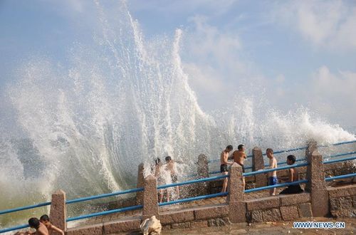 Visitors enjoy the waves as tropical storm Damrey approaches along coastal areas in Qingdao, East China's Shandong Province, August 1, 2012. Damrey is expected to land on the coast of Jiangsu and Shandong provinces on Thursday night or Friday morning. Photo: Xinhua