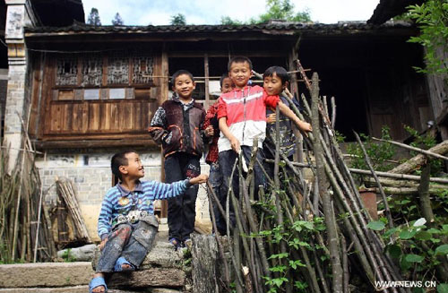 Children play in front of a 200-year-old house in the Labeng stockaded village of Lianshan Village, Libo County of southwest China's Guizhou Province, May 27, 2012. Lianshan Village is an area inhabited by the Bouyei ethnic group, with the Labeng stockaded village inside it being the most well-preserved part. Some of the houses in Labeng village are over 200 years old. Libo County was listed in the world heritage sites in 2007. Photo: Xinhua