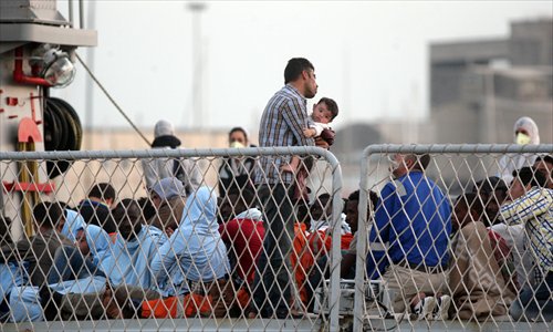 Survivors of a migrant boat shipwreck await evacuation on an Italian warship at Catania harbor in Sicily on Tuesday after being rescued, as Italy threatened to send asylum-seekers to other European countries if they don't receive more help to stem a wave of arrivals from North Africa. Dozens of medical personnel stood by to assist the survivors in four tents. 