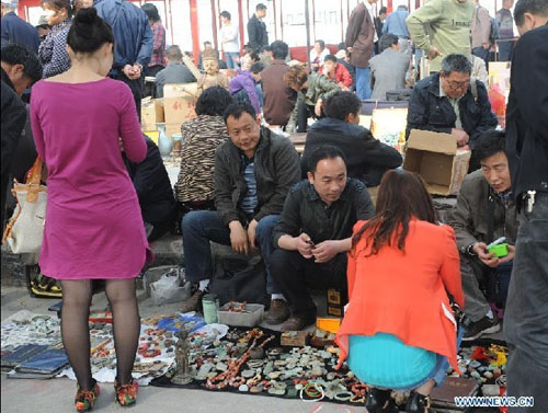 Customers choose curios at a flea market in Zhengzhou, capital of central China's Henan Province, April 14, 2012. The flea market of Zhengzhou Antique Market attracted many collectors everyday. Venders lay their goods on the ground, making the flea market a popular place for curios and antiques business. Photo: Xinhua