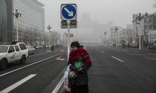 A citizen waits to cross a smoggy street in Beijing, the capital of China, on January 29, 2013. The National Meteorological Center (NMC) issued a code-blue alert on January 27 as the smoggy weather forecast for the following two days would cut visibility and worsen air pollution in some central and eastern Chinese cities. Photo: Li Hao/GT