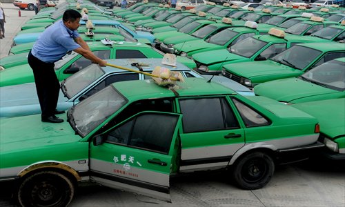 An official smashes the roof light of a fake taxi in Hefei, Anhui Province Monday. The city confiscated 156 clone taxis during a recent campaign. Photo: CFP