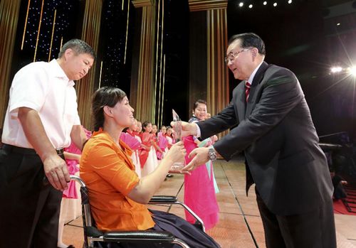 Li Changchun (R), a member of the Standing Committee of the Political Bureau of the Central Committee of the Communist Party of China, awards Zhang Lili, a teacher who lost her legs while saving two students from an onrushing bus, during a performance celebrating the upcoming Teachers' Day in Beijing, September 4, 2012. Photo: Xinhua