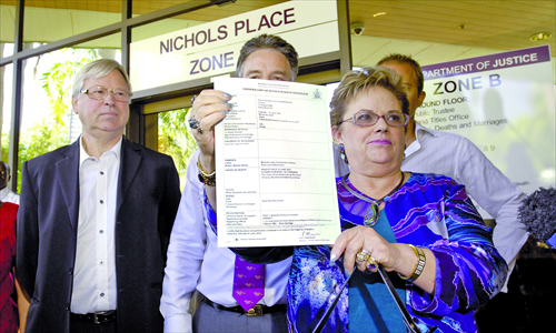 Lindy Chamberlain-Creighton (right) shows off daughter Azaria's death certificate in Darwin yesterday as ex-husband Michael Chamberlain (left) looks on after a coroner ruled that a dingo snatched baby Azaria Chamberlain from a tent in the Australian desert 32 years ago ending a case that caused a global sensation. Photo: AFP/AAP/Patrina MALONE 