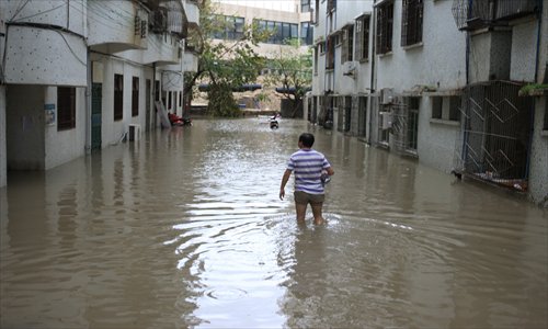 A man walks through floodwater at a residential compound in Sanya, Hainan Province, on Sunday. More than 80,000 people in Hainan have been relocated following the arrival of Typhoon Son-Tinh, which has brought gales and downpours to the region since Saturday. Photo: CFP