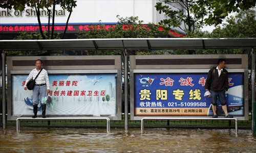 Two commuters avoid the water at a bus stop on Zhennan Road. Photo: Cai Xianmin/GT