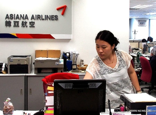 An employee works at the office of the Asiana Airlines to Shanghai, east China, July 7, 2013. A total of 141 Chinese citizens were among the 291 passengers aboard the Asiana Airlines flight that crash-landed at the San Francisco International Airport on Saturday, and 90 of the Chinese passengers in total departed from Shanghai via Seoul to the San Francisco airport in the U.S. All the two killed in the crash were identified to be Chinese women, South Korea's transportation ministry said Sunday. (Xinhua/Chen Fei)  